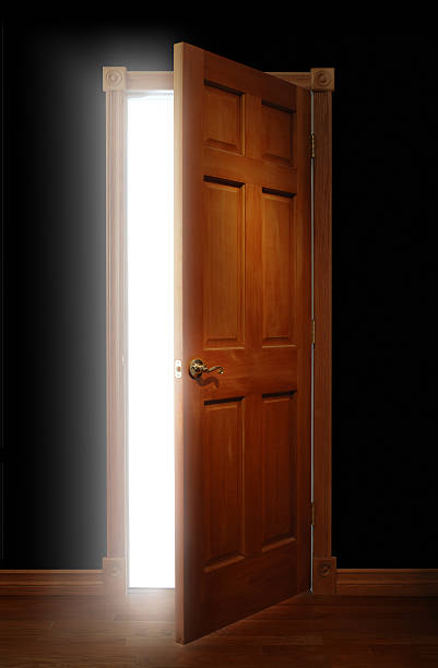 Wooden door standing open representing opportunity Door opening with bright light illuminating a dark space ajar stock pictures, royalty-free photos & images