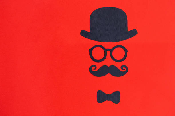 Male silhouette with mustache, glasses and hat patterns on the red background. Movember concept. Prostate Cancer and men's health awareness. Funny party faces. Copy space