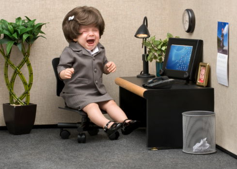 Baby dressed in professional office attire crying at her desk