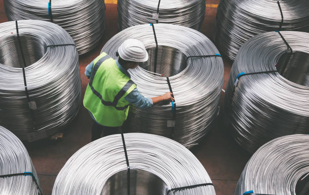 Young engineer man checking production line in wire warehouse Overview of young quality inspector man checking production line and testing quality of steel pipe coils at warehouse section in cable factory. XXXL metal industry photos stock pictures, royalty-free photos & images