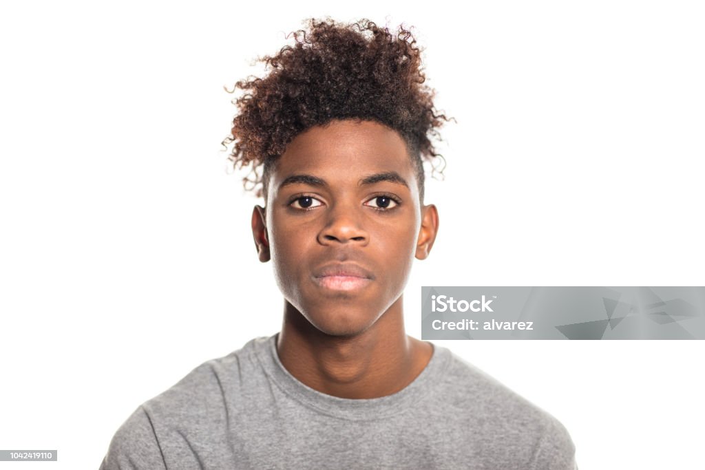 Close-up of serious looking teenager Close-up portrait of serious looking teenager. African teenage boy looking at camera against white background. Portrait Stock Photo