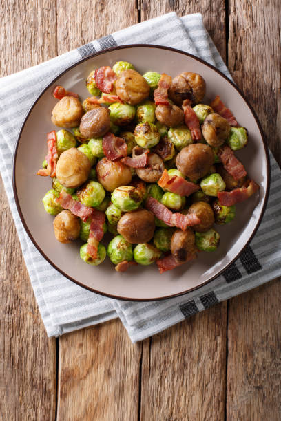 istock Fried chestnuts, brussels sprouts and bacon closeup. Vertical top view 1042419780