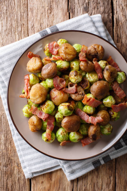 istock Delicious appetizer: roasted chestnuts, Brussels sprouts and bacon close-up. Vertical top view 1042419924