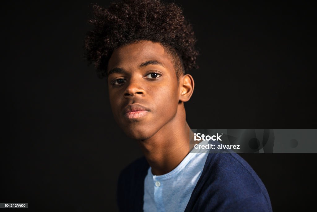 Teenager with afro hair style Close-up portrait of confident young man in casuals looking at camera. Teenager with afro hair on black background. Teenager Stock Photo