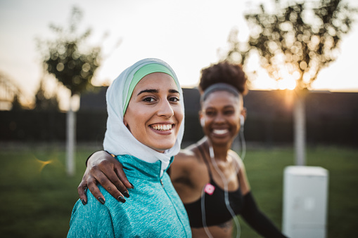 Two young women, different ethnicity ,exercisng outdoor. They are wearing sport clothing.
Getting ready for training.