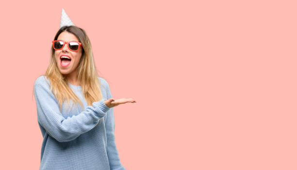 istock Young woman celebrates birthday holding something in empty hand 1042426100