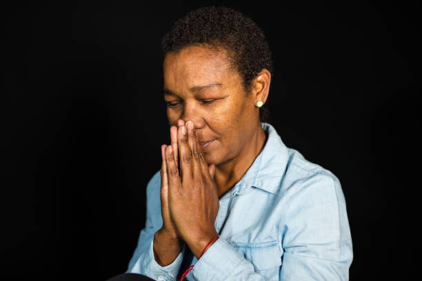portret van senior afrikaanse vrouw bidden - ogen dicht closeup vrouw 50 jaar stockfoto's en -beelden