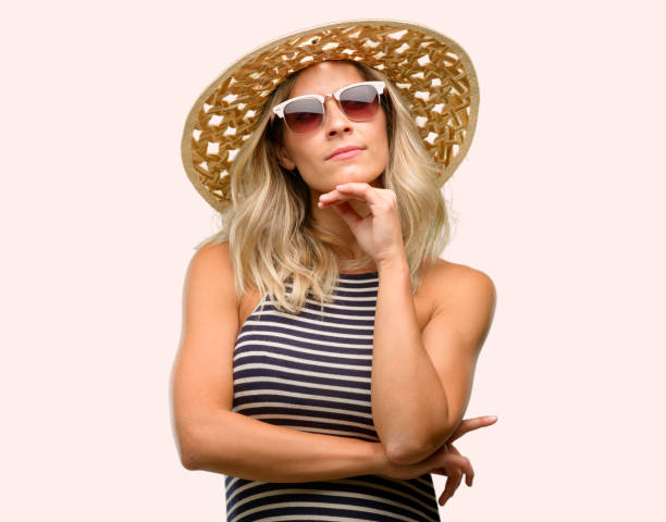 istock Young woman using sunglasses wearing summer hat thinking and looking up expressing doubt and wonder 1042437158
