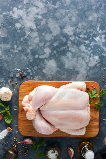 istock Prepared fresh raw chicken for cooking on a cutting wooden board, top view, selective focus 1042438080