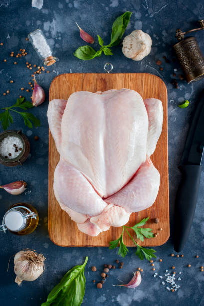 istock Prepared fresh raw chicken for cooking on a cutting wooden board, top view, selective focus 1042438098