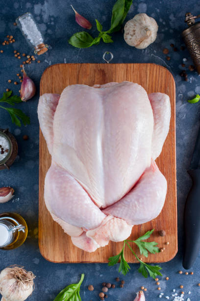 istock Prepared fresh raw chicken for cooking on a cutting wooden board, top view, selective focus 1042438116