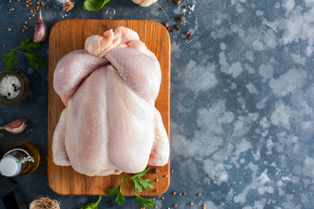 istock Prepared fresh raw chicken for cooking on a cutting wooden board, top view, selective focus 1042438120
