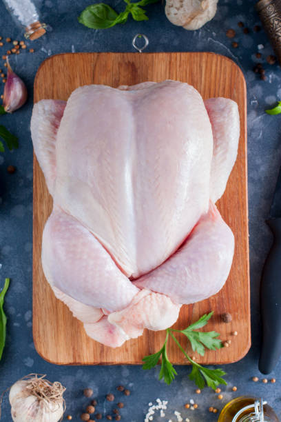 istock Prepared fresh raw chicken for cooking on a cutting wooden board, top view, selective focus 1042438124