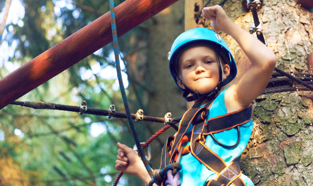 petit garçon dans un casque de protection et un équipement spécial passe un parcours du combattant à hauteur - high up obstacle course ropes course teenage boys photos et images de collection