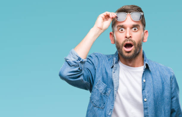 young handsome man wearing sunglasses over isolated background afraid and shocked with surprise expression, fear and excited face. - surprise imagens e fotografias de stock