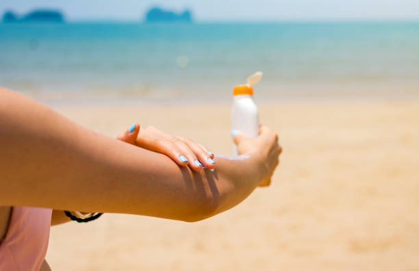 Girl applying sun lotion on her hands at the beach