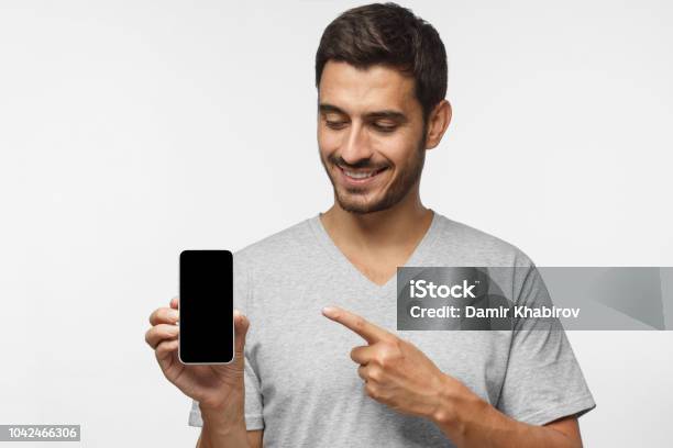 Foto de Retrato De Homem Feliz Demonstrando O Smartphone Em Branco E Apontando Para A Tela Em Branco Vazia Com Sorriso Copyspace Para Yor App e mais fotos de stock de Homens