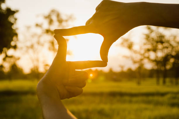 istock Close up of hands making frame gesture. Close up of woman hands making frame gesture with sunset. 1042471484