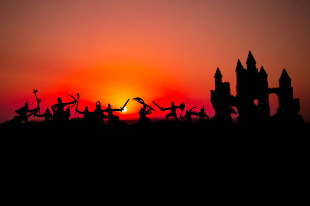 istock Medieval battle scene with cavalry and infantry. Silhouettes of figures as separate objects, fight between warriors on sunset foggy background. 1042478638