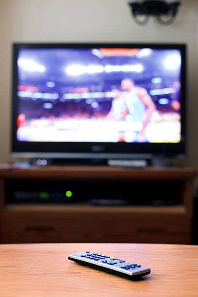istock Remote control on table with TV showing basketball game 104249380