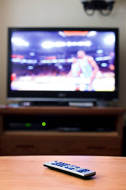 Remote control on table with TV showing basketball game Remote control on a table with TV showing sports remote control on table stock pictures, royalty-free photos & images