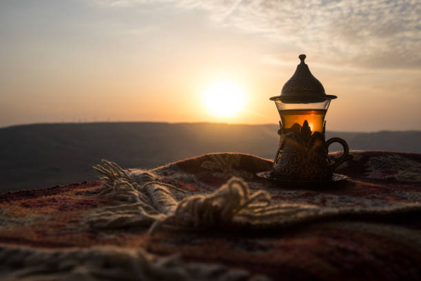 istock Arabian tea in glass on a eastern carpet. Eastern tea concept. Armudu traditional cup. Sunset background. Selective focus 1042494458
