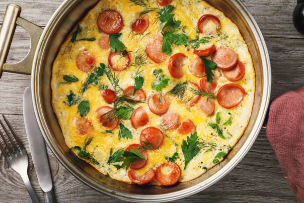 istock Scrambled eggs with sausage and greens in a frying pan, top view 1042508992