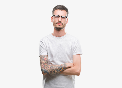 Young tattooed adult man skeptic and nervous, disapproving expression on face with crossed arms. Negative person.