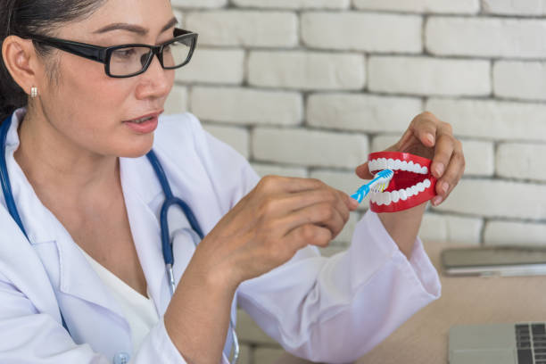 istock Mature Doctor Brushing Dentures In Clinic 1042517444