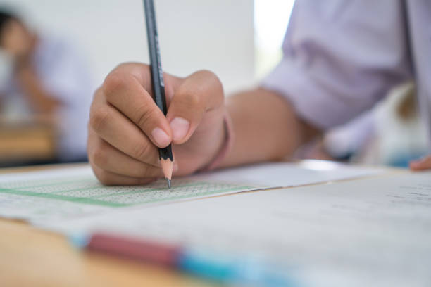 istock Asian Boy Students taking exams, writing examination room with undergraduate students inside. Student sitting learning lessons on row desk chair doing final exam in classroom with uniform. 1042534042