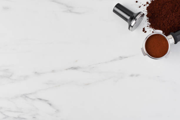 istock Coffee tamper and portafilter with gorund coffee on white marble 1042535608