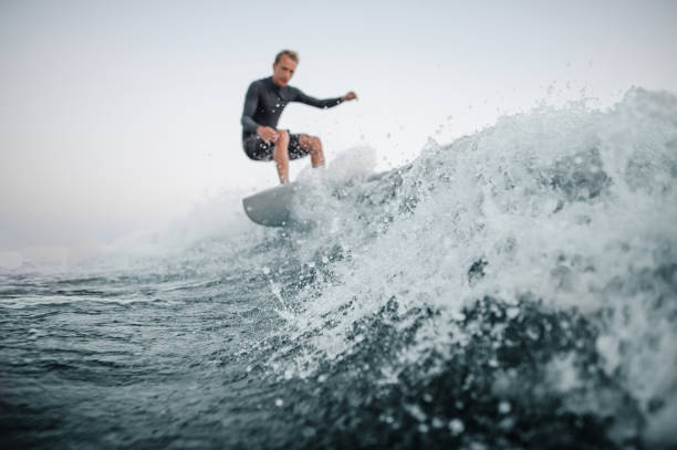 istock Blurred wakesurfer riding down the wave in focus on a foreground 1042539346