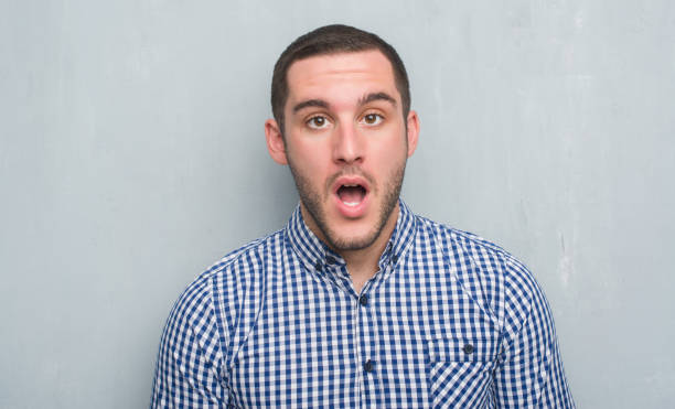 istock Young caucasian man over grey grunge wall scared in shock with a surprise face, afraid and excited with fear expression 1042539592