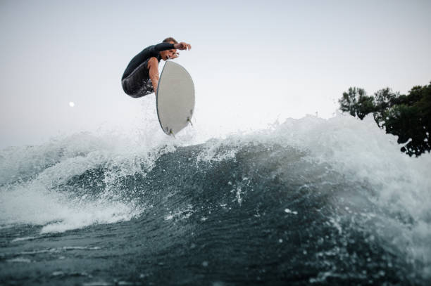 istock Young and active wakeboarder jumping on the blue splashing wave against the background of clear sky on the foreground 1042539792