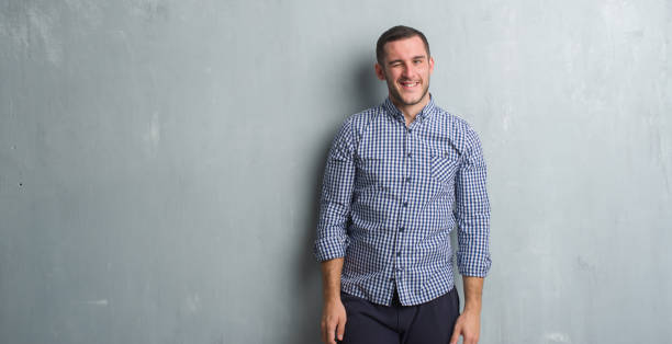 istock Young caucasian man over grey grunge wall winking looking at the camera with sexy expression, cheerful and happy face. 1042542940