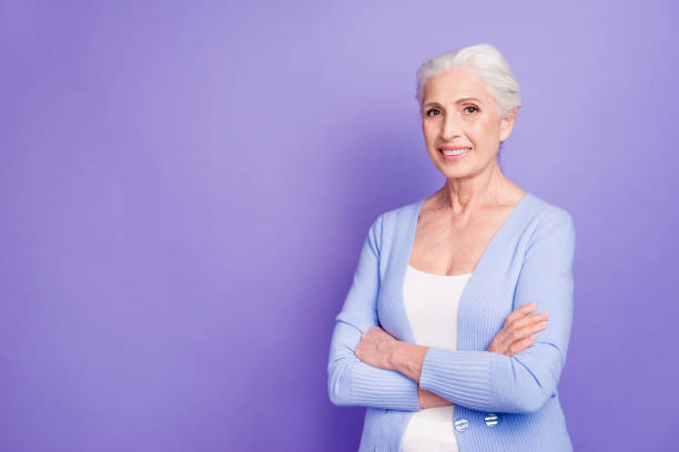 istock Grey haired old nice beautiful smiling woman with crossed hands, copy blank empty space. Isolated over violet purple background 1042544778