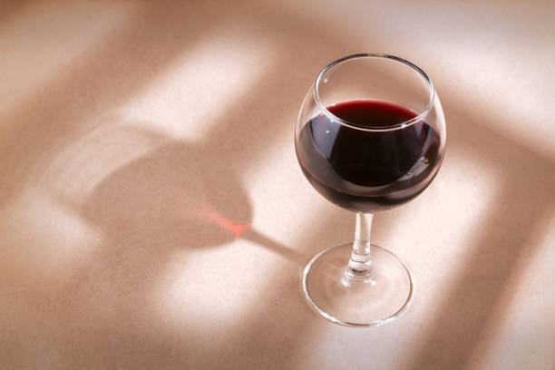 istock Red wine glass on the table with window shadow 1042553816
