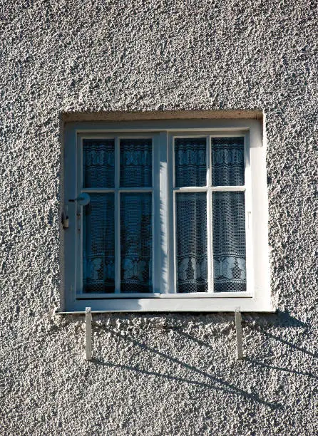 Windows in the middle of rough plaster on old building in Munich, Sendling-Westpark
