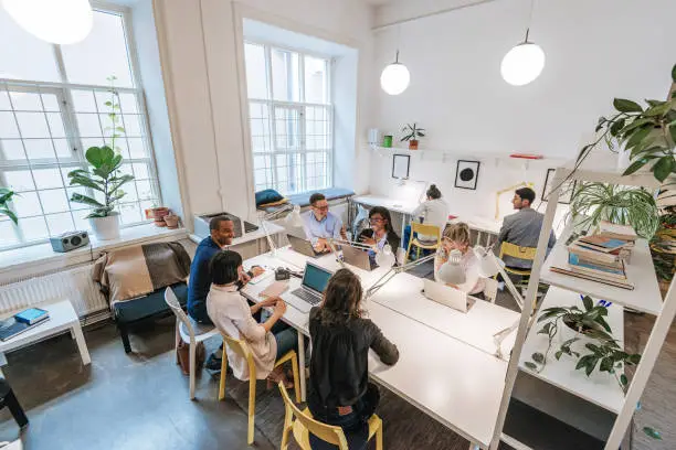 Coworkers working in modern co-working space in Scandinavia. Multi-ethnic group of young business professionals, start-up establishers, freelancers working and developing together.