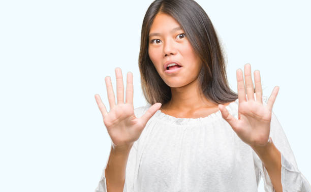 istock Young asian woman over isolated background afraid and terrified with fear expression stop gesture with hands, shouting in shock. Panic concept. 1042576108