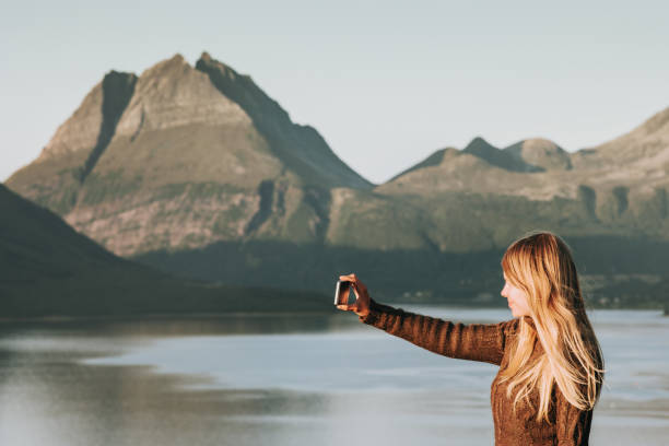 frau touristen nehmen selfie von smartphone reisen lifestyle konzept abenteuer urlaub im freien norwegen sonnenuntergang bergen und meer-landschaft - 11829 stock-fotos und bilder