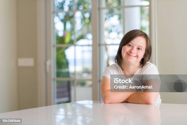 Downsyndromfrau Im Hause Glückliches Gesicht Lächelnd Mit Verschränkten Armen In Die Kamera Schaut Positiver Mensch Stockfoto und mehr Bilder von Andersfähigkeiten