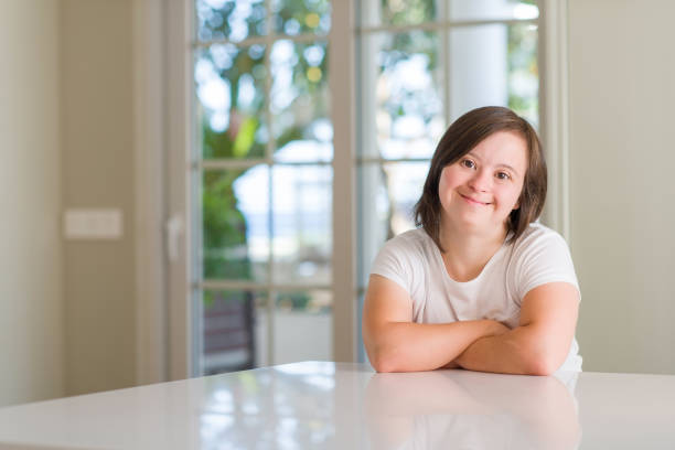 Down syndrome woman at home happy face smiling with crossed arms looking at the camera. Positive person. Down syndrome woman at home happy face smiling with crossed arms looking at the camera. Positive person. disabled adult stock pictures, royalty-free photos & images