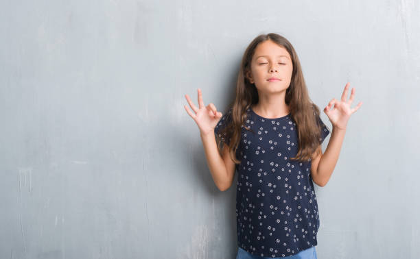 Young hispanic kid over grunge grey wall relax and smiling with eyes closed doing meditation gesture with fingers. Yoga concept. Young hispanic kid over grunge grey wall relax and smiling with eyes closed doing meditation gesture with fingers. Yoga concept. mindfulness children stock pictures, royalty-free photos & images