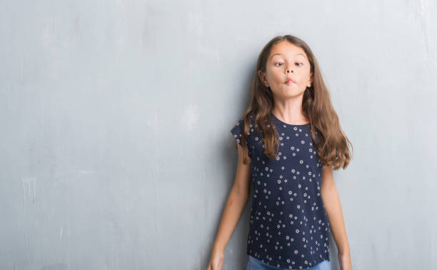 istock Young hispanic kid over grunge grey wall making fish face with lips, crazy and comical gesture. Funny expression. 1042586290