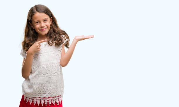 istock Brunette hispanic girl amazed and smiling to the camera while presenting with hand and pointing with finger. 1042589728