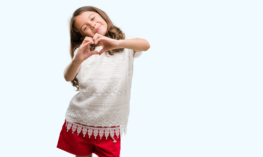 Brunette hispanic girl smiling in love showing heart symbol and shape with hands. Romantic concept.