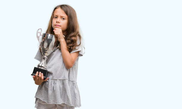 istock Brunette hispanic girl holding a trophy serious face thinking about question, very confused idea 1042593048