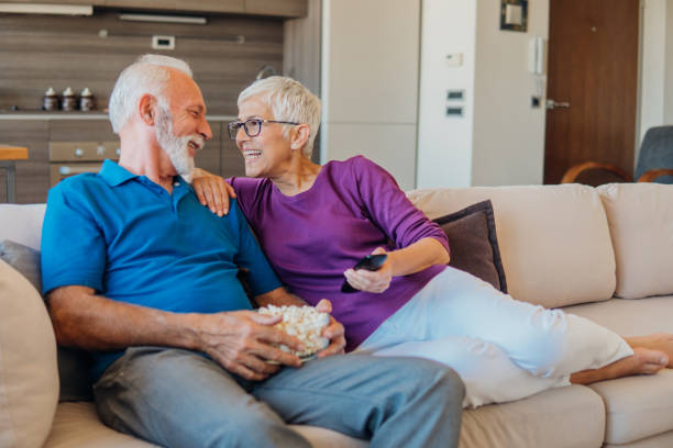 istock Elderly couple holding remote control and eating popcorn 1042599602