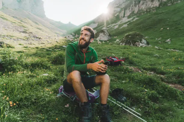 Young Caucasian man resting while  hiking in Swiss Alps in Appenzell